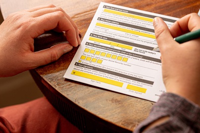 Close up of a male completing a paper Voter Registration form